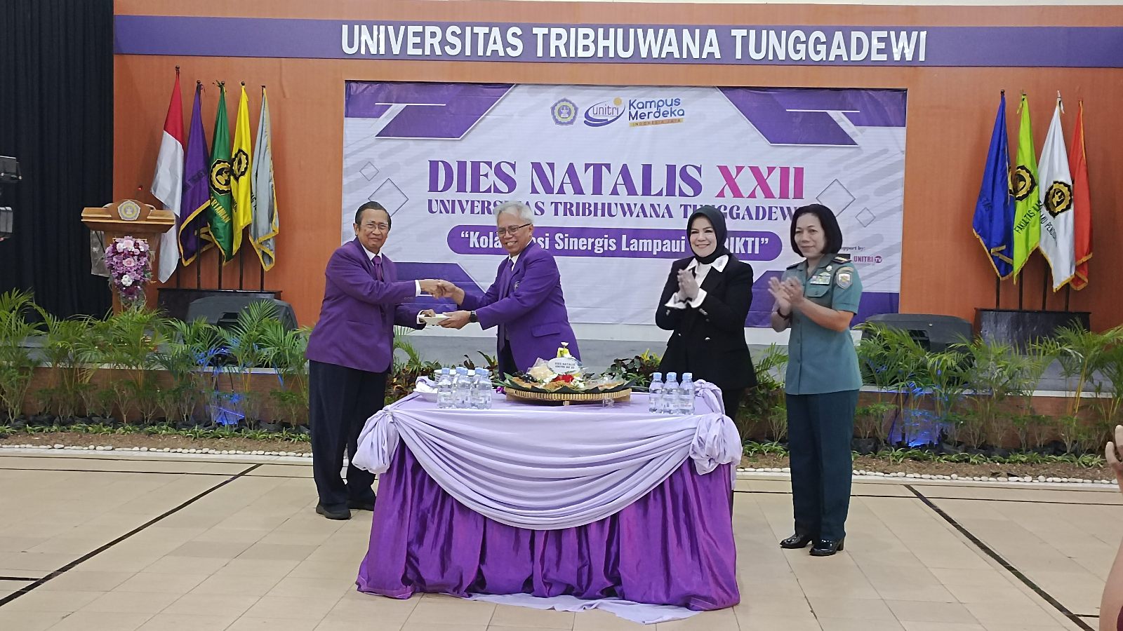 Rektor UNITRI menyerahkan potongan pertama tumpeng kepada Ketua Yayasan. (Foto: Agus N/reportasemalang)